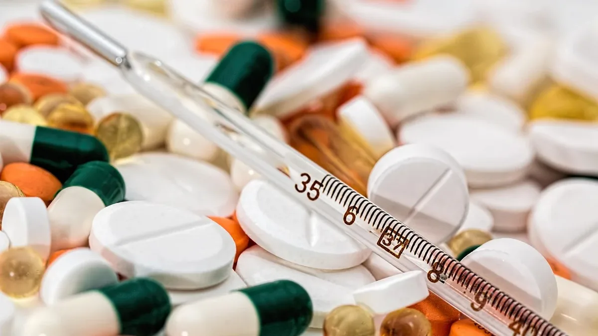 A collection of pills and a thermometer.